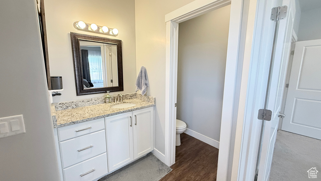 Bathroom with vanity, toilet, wood finished floors, and baseboards