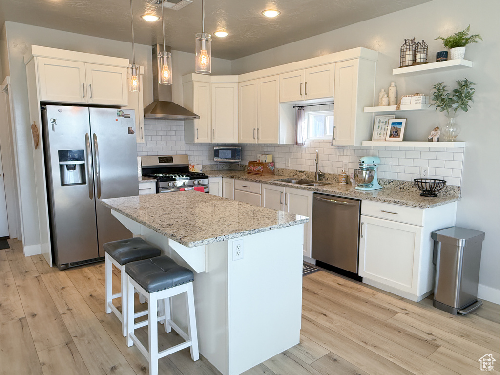 Kitchen featuring stainless steel appliances, wall chimney exhaust hood, light wood-style flooring, open shelves, and recessed lighting