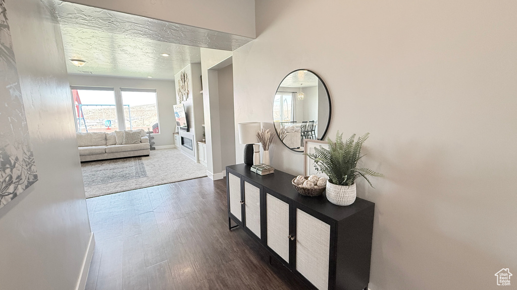 Hall featuring baseboards, dark wood-type flooring, and a textured ceiling