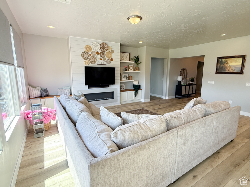 Living room with light wood finished floors, recessed lighting, and a textured ceiling