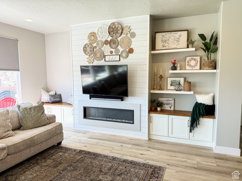 Living area featuring light wood-style flooring, a large fireplace, and recessed lighting