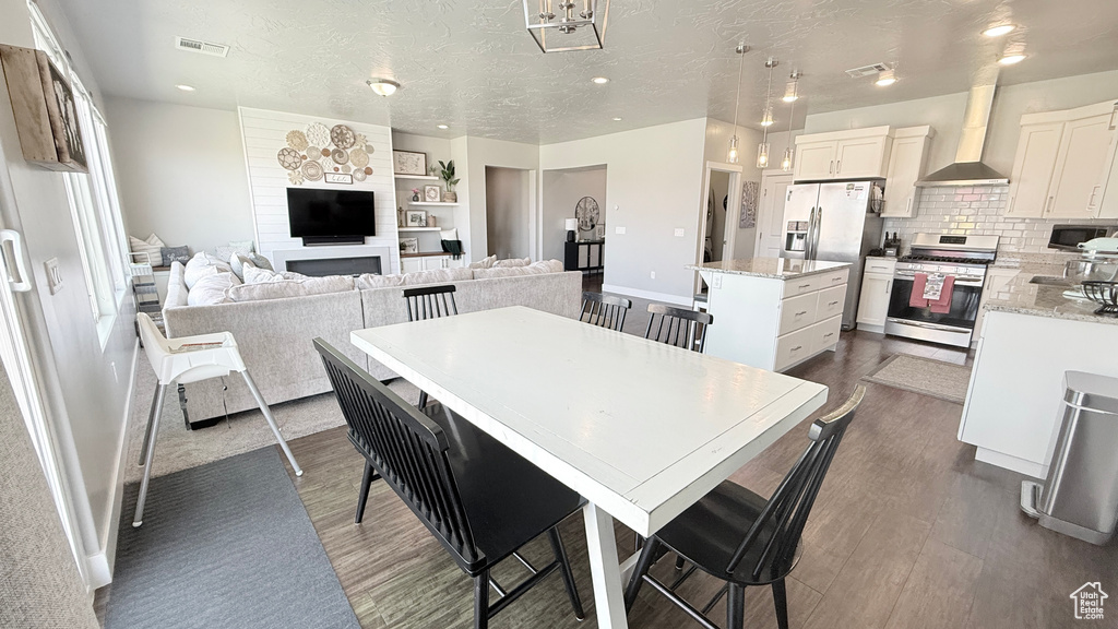 Dining room featuring dark wood-style floors, baseboards, a textured ceiling, and recessed lighting