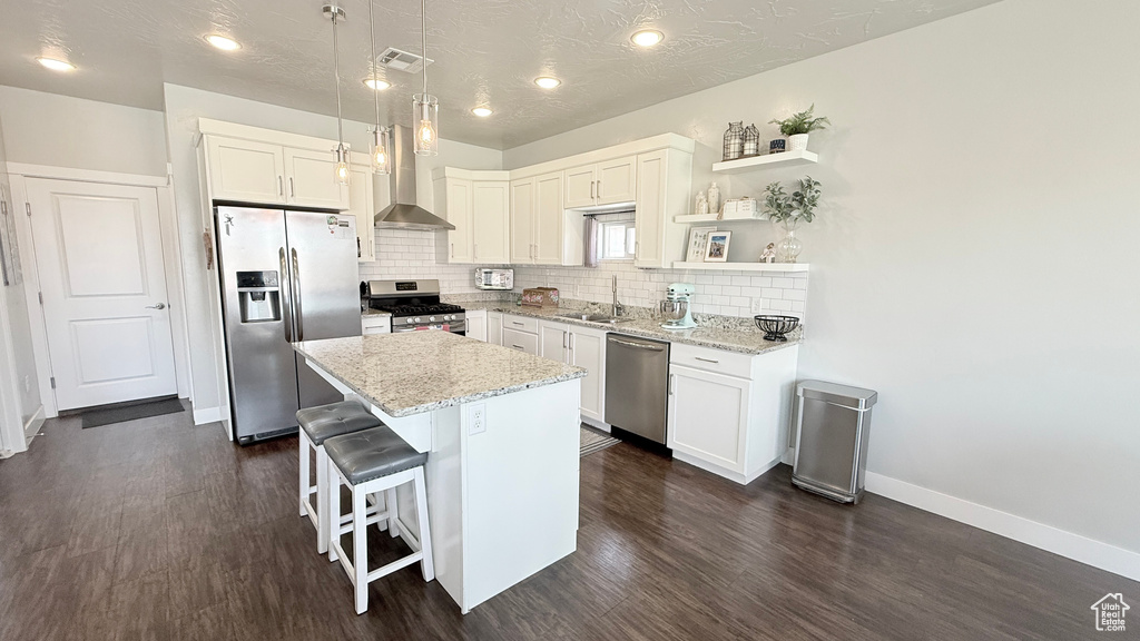 Kitchen with stainless steel appliances, dark wood-style flooring, tasteful backsplash, a kitchen island, and a sink