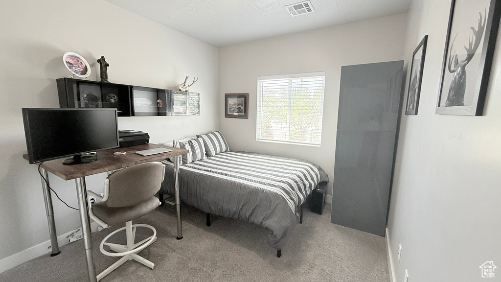 Carpeted bedroom with baseboards and a desk
