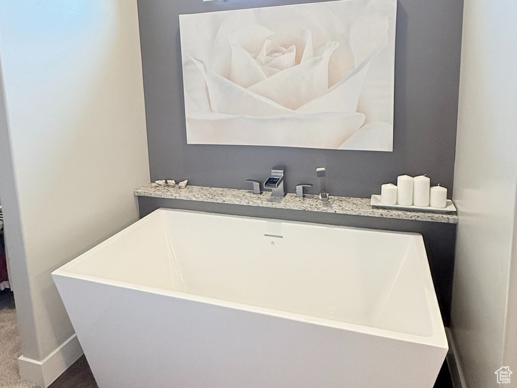 Bathroom featuring wood finished floors, a freestanding bath, and baseboards