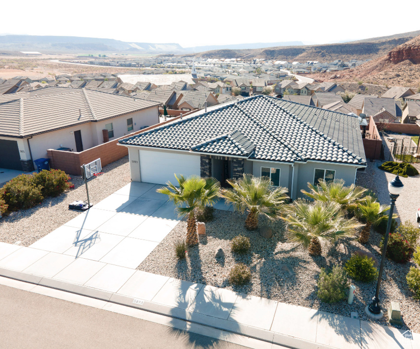 View of front of property with a garage, concrete driveway, a tiled roof, a residential view, and a mountain view