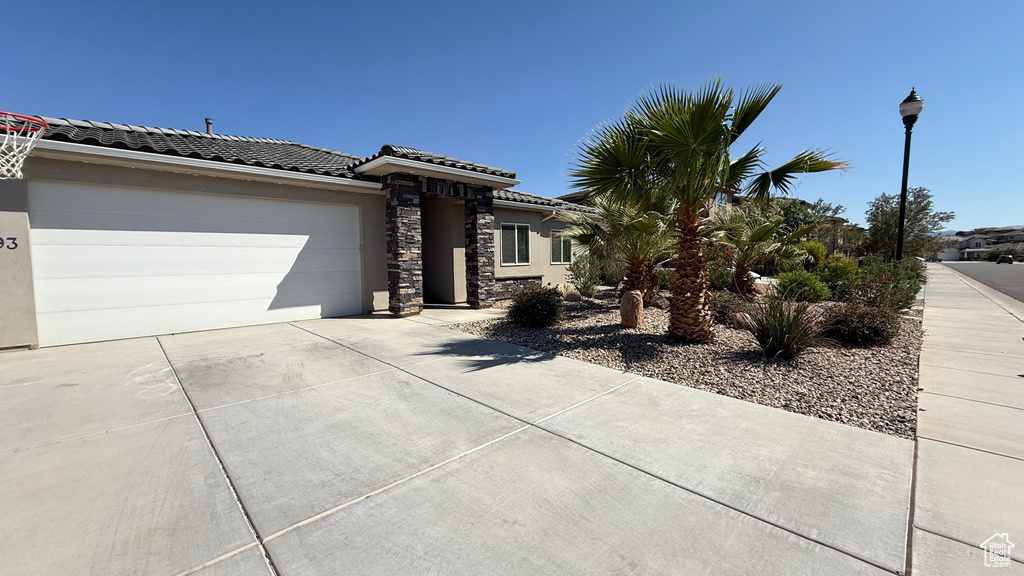 View of front of home featuring concrete driveway, an attached garage, a tiled roof, and stucco siding