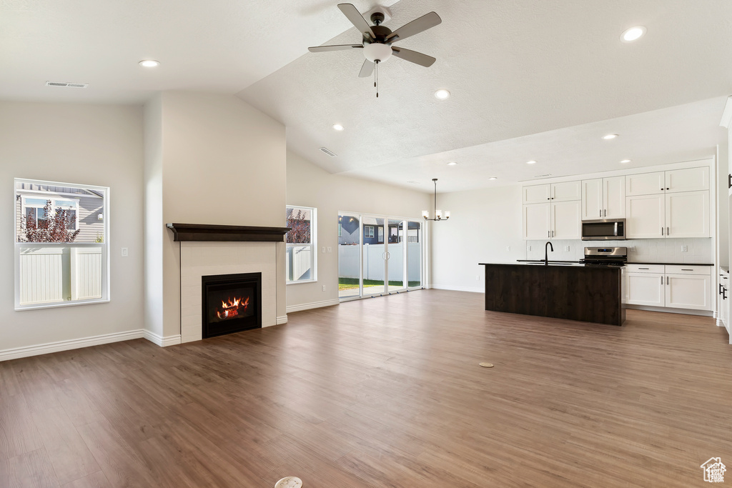 Unfurnished living room with a sink, lofted ceiling, a ceiling fan, light wood-style flooring, and recessed lighting