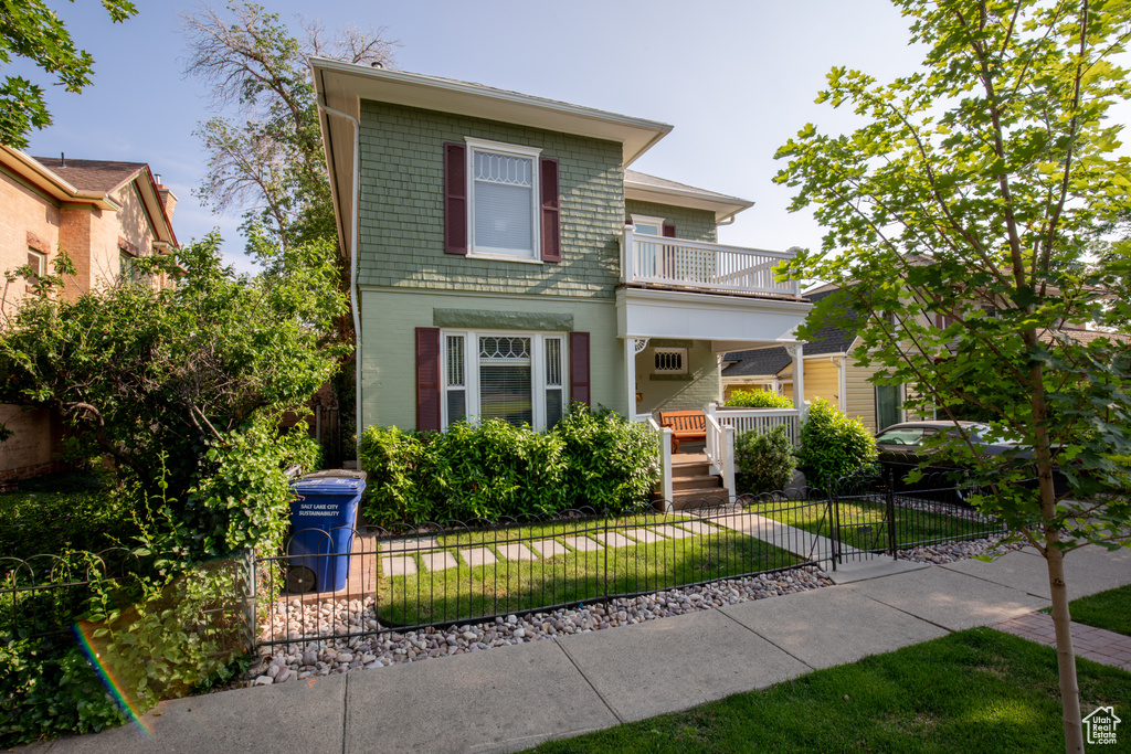 View of front of home with a fenced front yard and a balcony