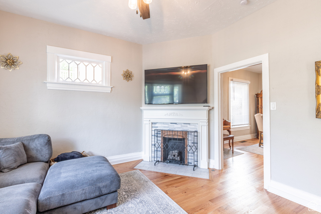 Living room featuring ceiling fan, baseboards, wood finished floors, and a tile fireplace
