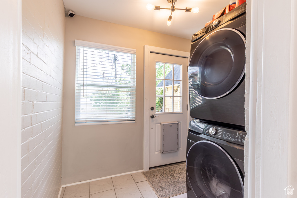 Laundry room with stacked washer / dryer, baseboards, and tile patterned floors