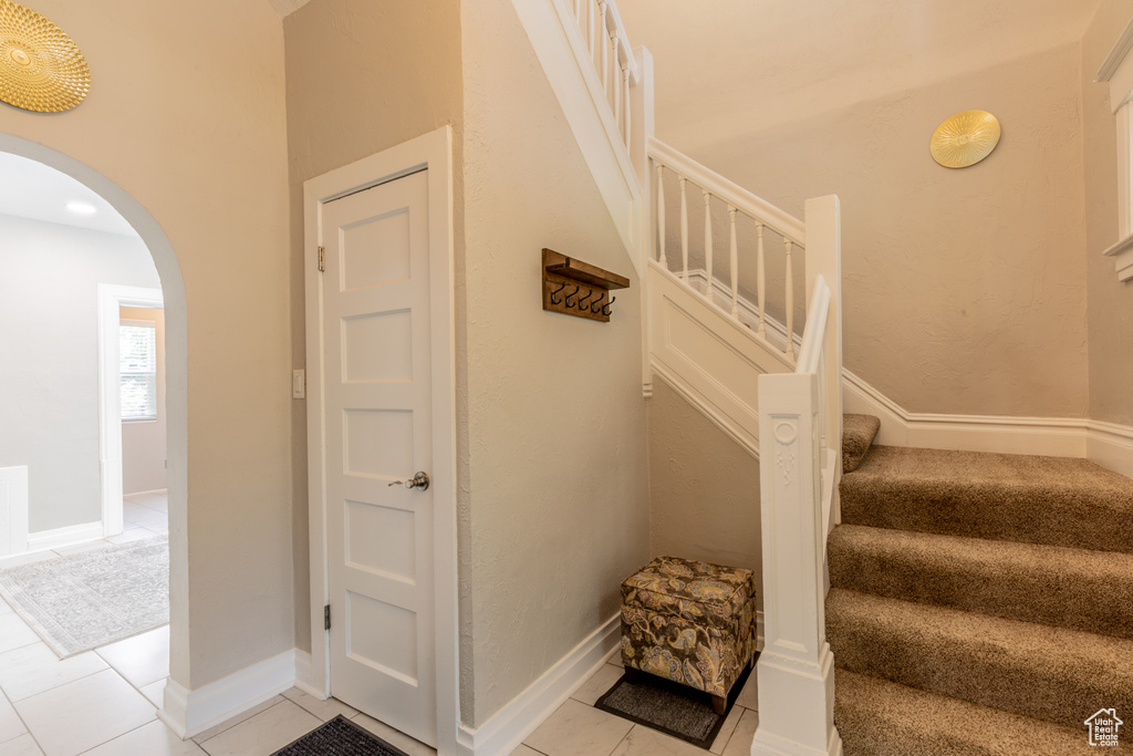 Stairs featuring arched walkways, tile patterned flooring, and baseboards