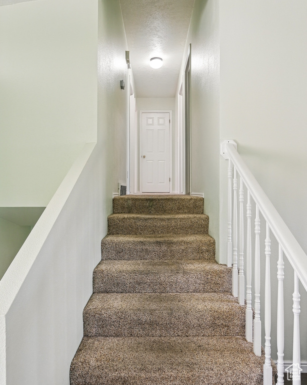 Staircase featuring a textured ceiling