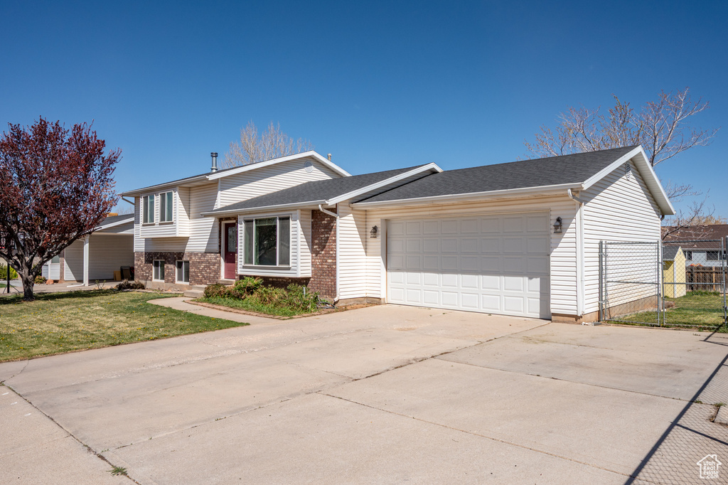 Tri-level home featuring a garage, brick siding, and driveway