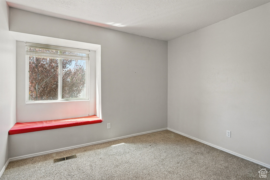Carpeted spare room featuring baseboards