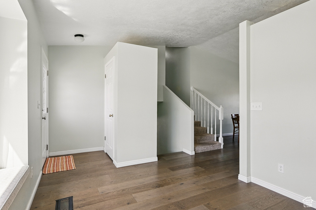 Empty room featuring wood finished floors, stairs, and baseboards