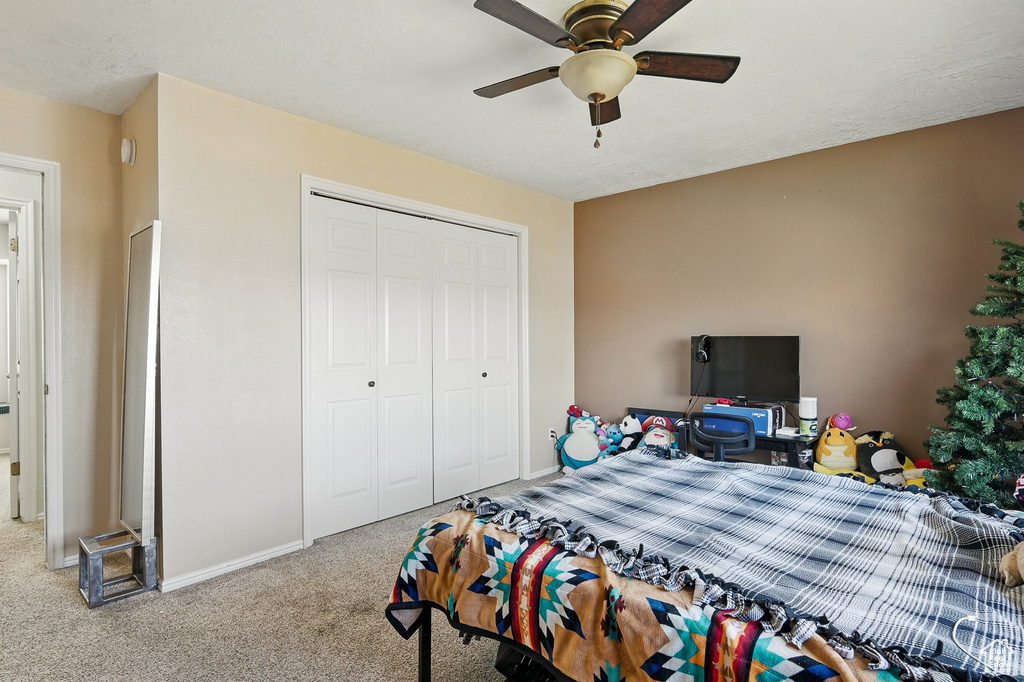 Carpeted bedroom with a closet, baseboards, and a ceiling fan