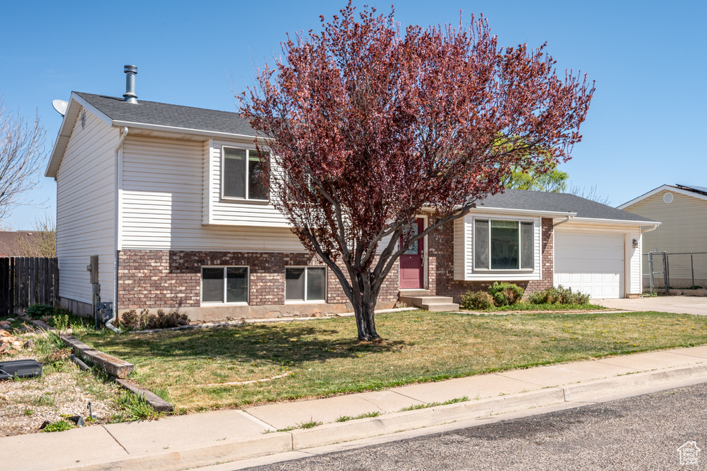 View of front of house with brick siding, an attached garage, and driveway