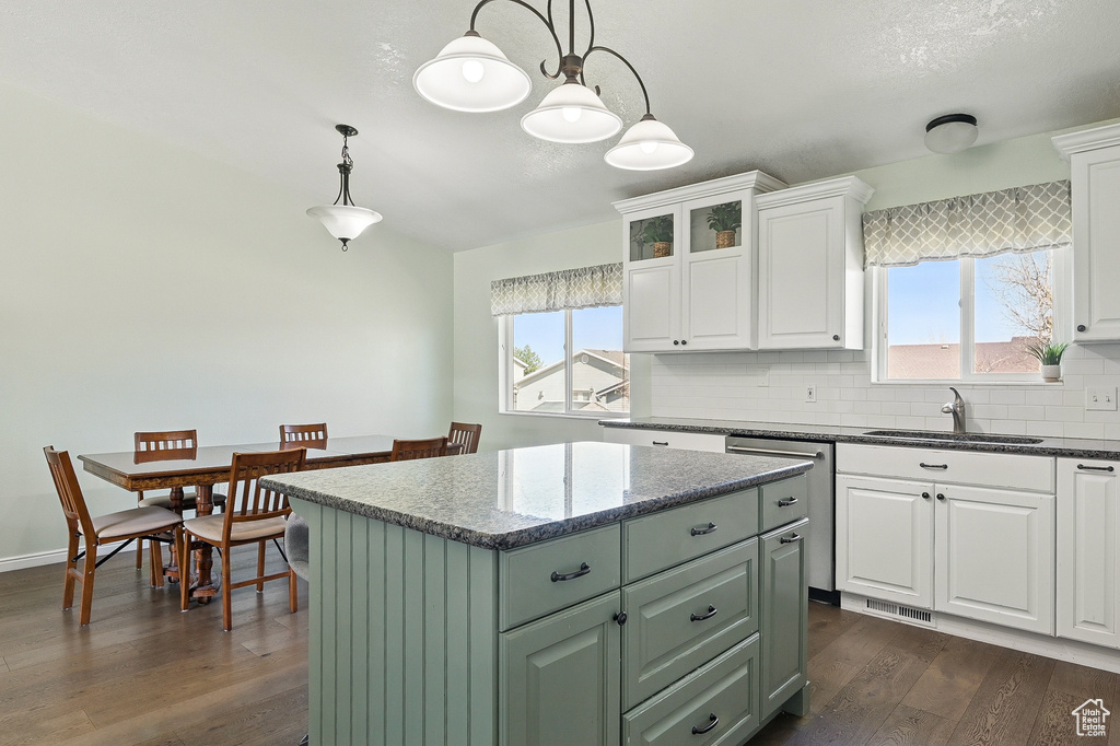 Kitchen featuring a sink, stainless steel dishwasher, a center island, dark wood-style floors, and white cabinets