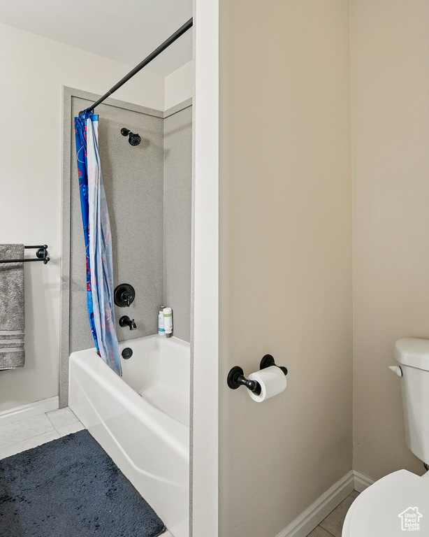 Bathroom featuring toilet, shower / bath combo with shower curtain, and baseboards