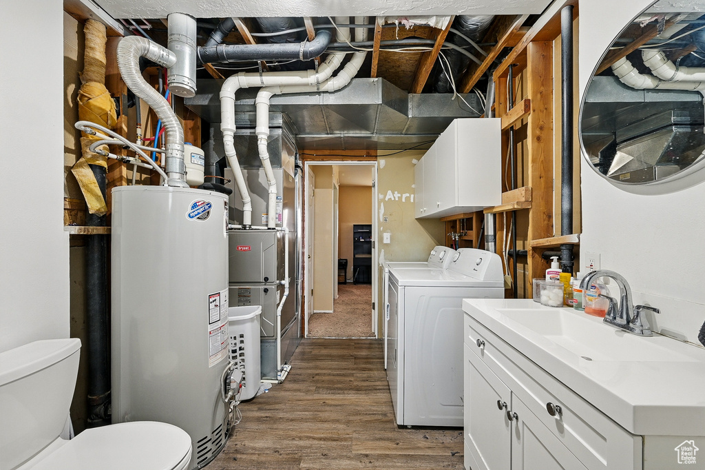 Laundry room featuring water heater, washing machine and dryer, and wood finished floors