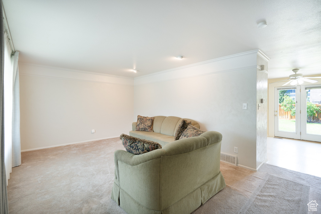 Sitting room featuring light carpet, crown molding, ceiling fan, and baseboards