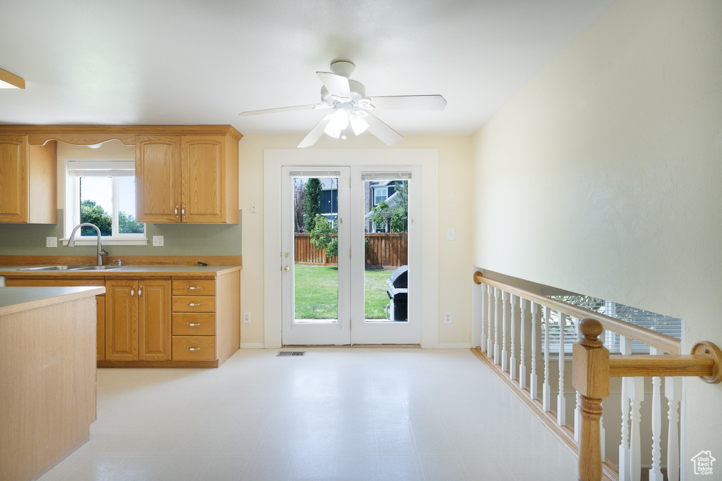 Kitchen featuring a sink, a ceiling fan, light floors, and light countertops