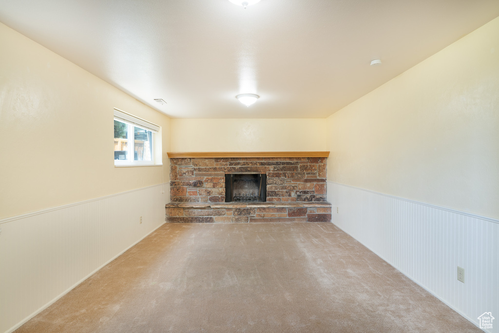 Unfurnished living room with a fireplace, a wainscoted wall, and carpet
