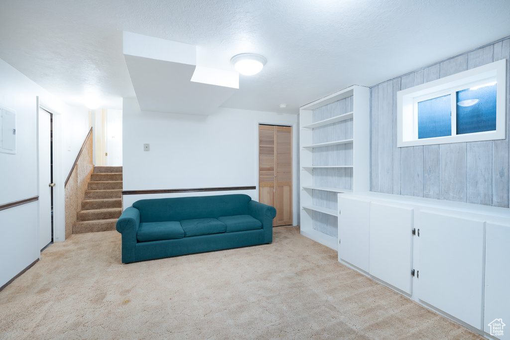 Sitting room with light colored carpet, stairway, and electric panel