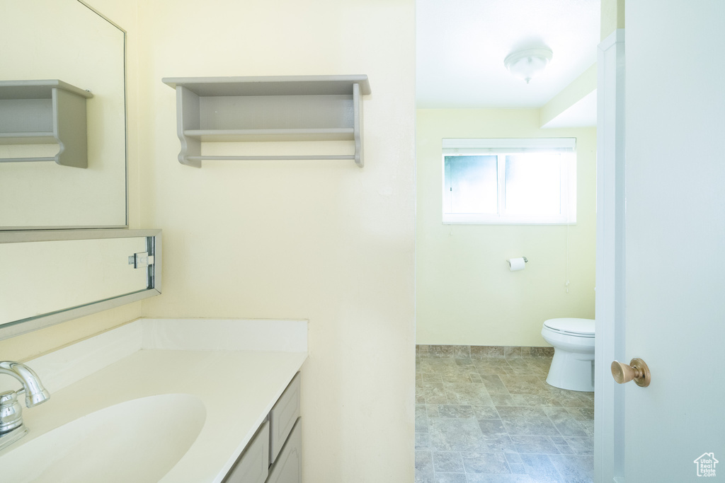 Bathroom with vanity, toilet, and stone finish flooring