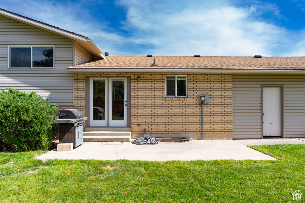 Back of property with entry steps, brick siding, a yard, and a patio area