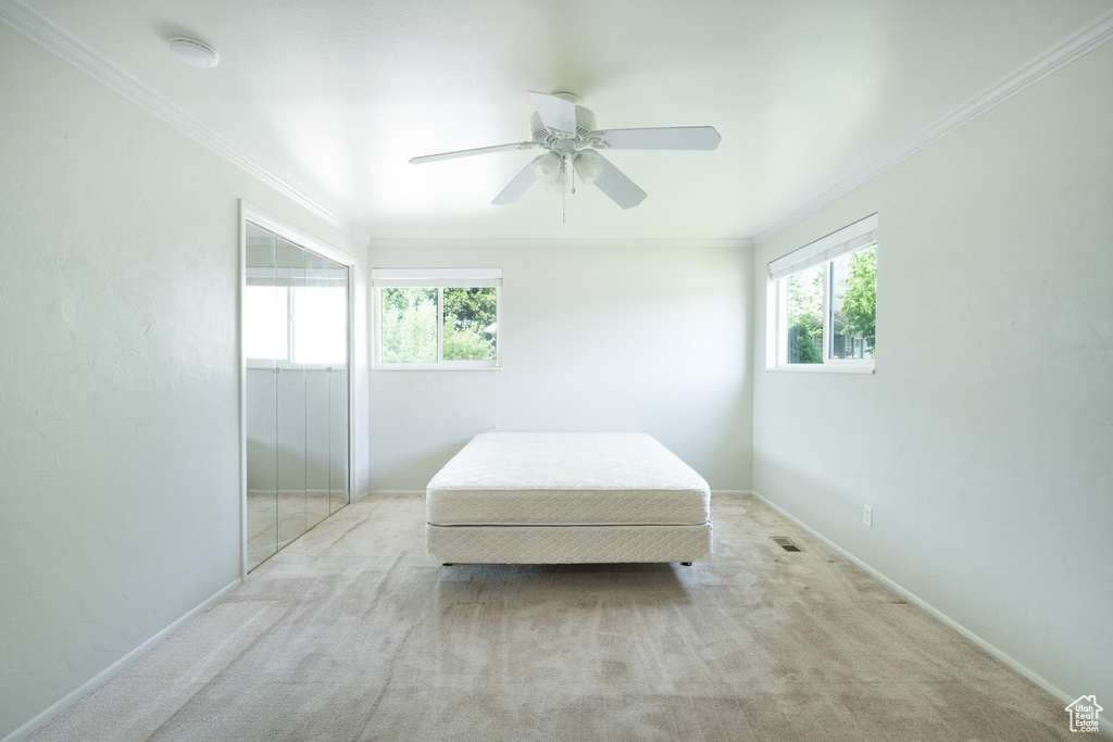 Bedroom with ornamental molding, light carpet, and ceiling fan