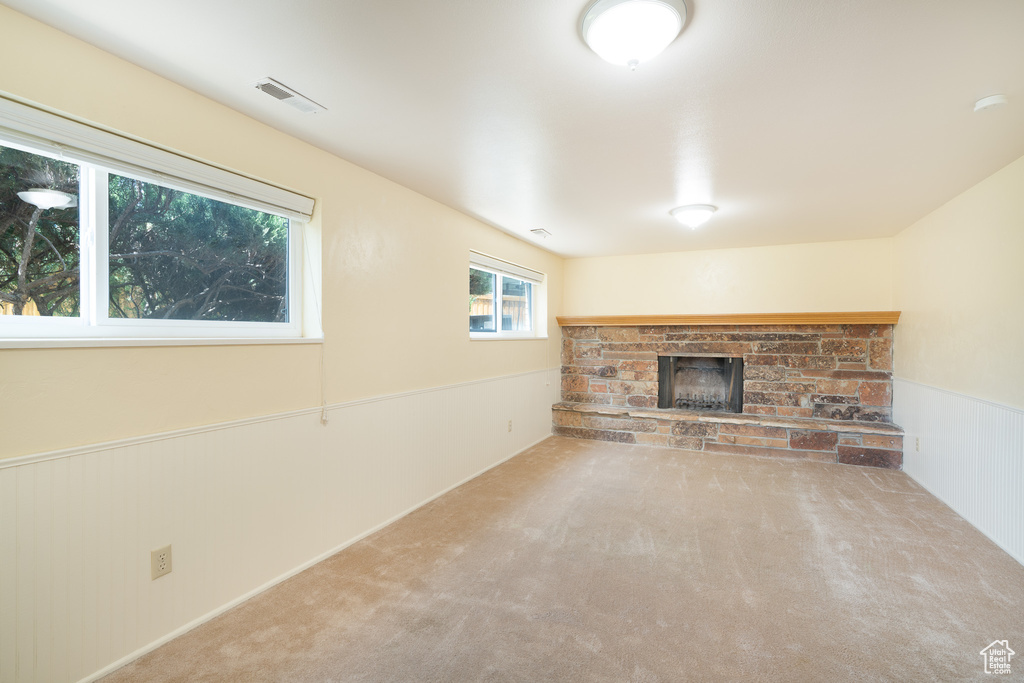 Unfurnished living room featuring a fireplace, carpet, and wainscoting