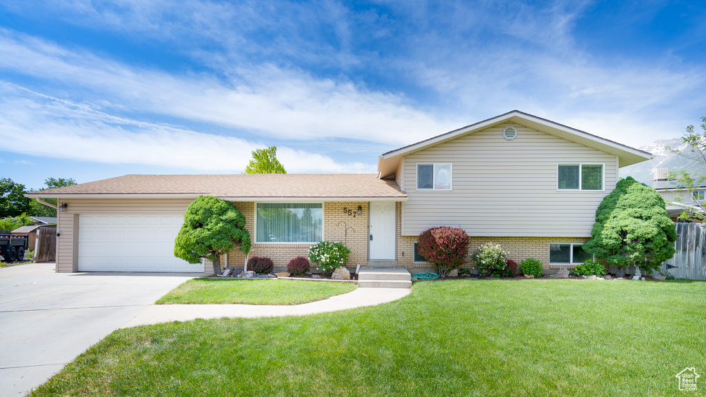 Tri-level home with brick siding, concrete driveway, and an attached garage