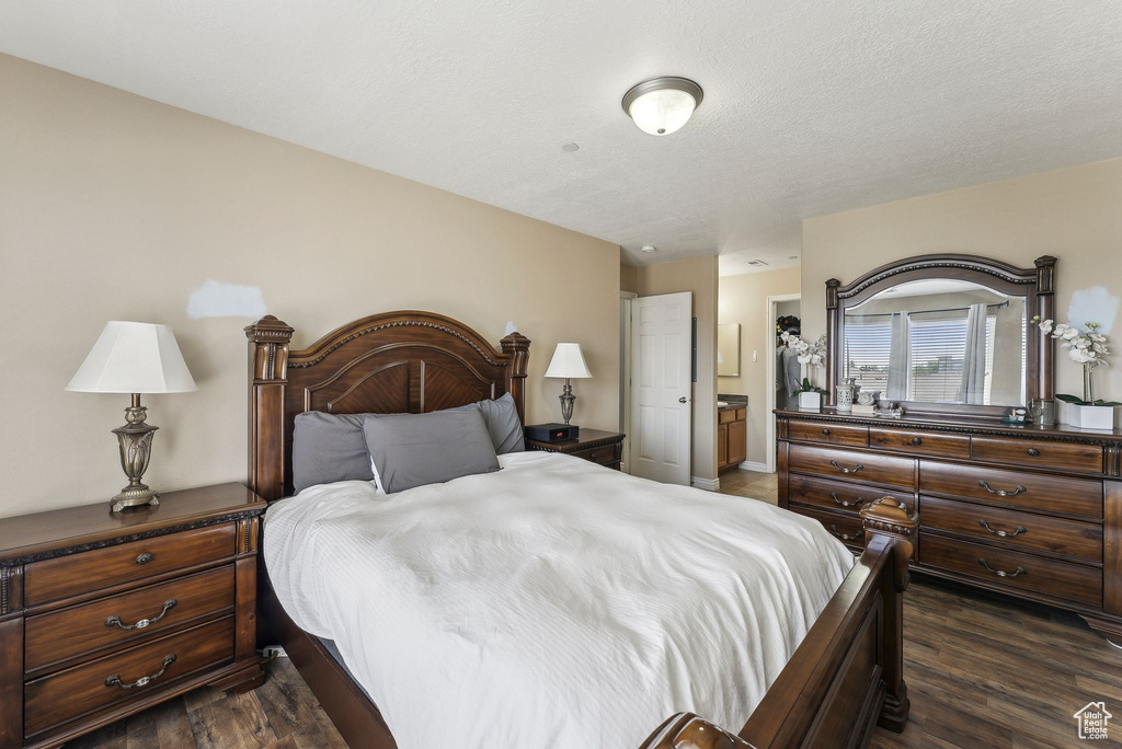 Bedroom with dark wood-type flooring and connected bathroom