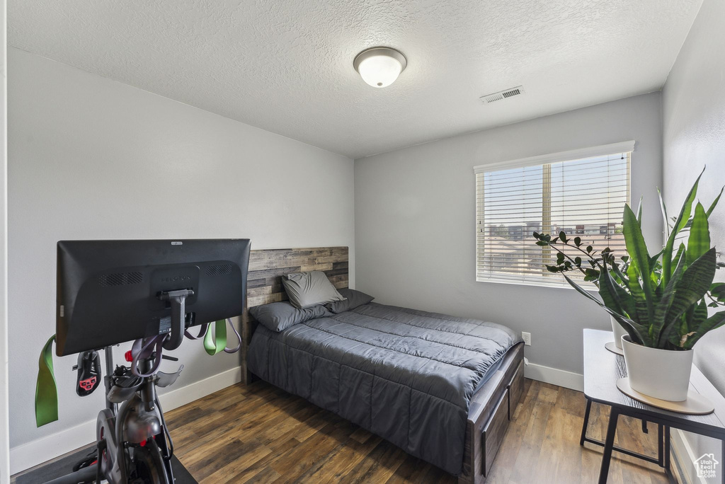 Bedroom featuring a textured ceiling, wood finished floors, and baseboards