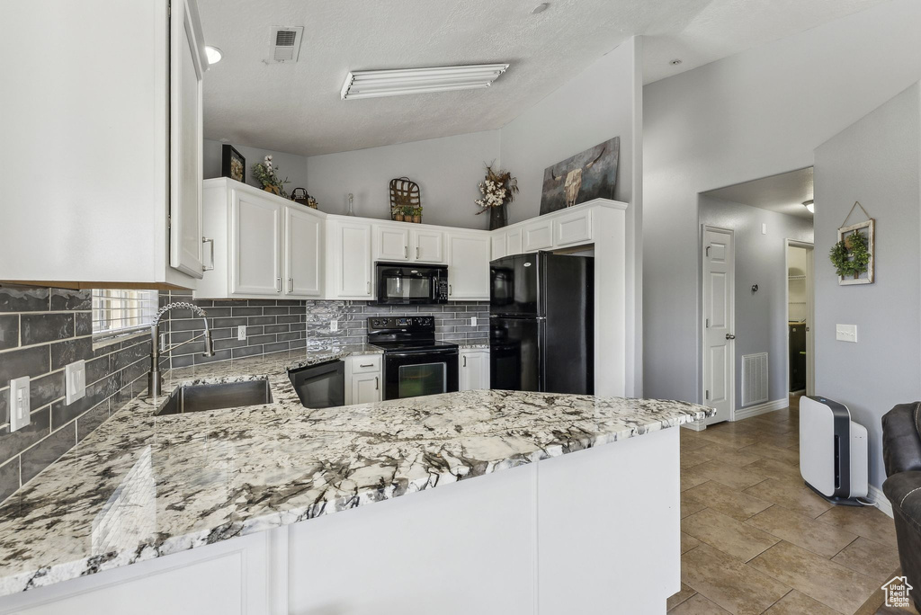 Kitchen featuring black appliances, a sink, backsplash, white cabinetry, and light stone counters
