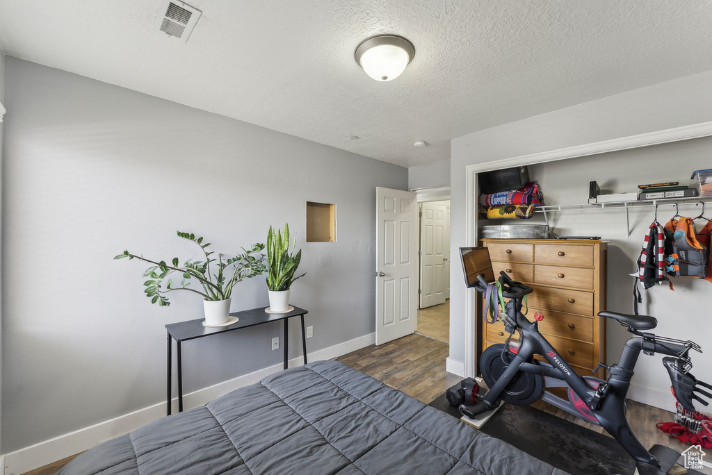 Bedroom featuring wood finished floors, baseboards, and a textured ceiling