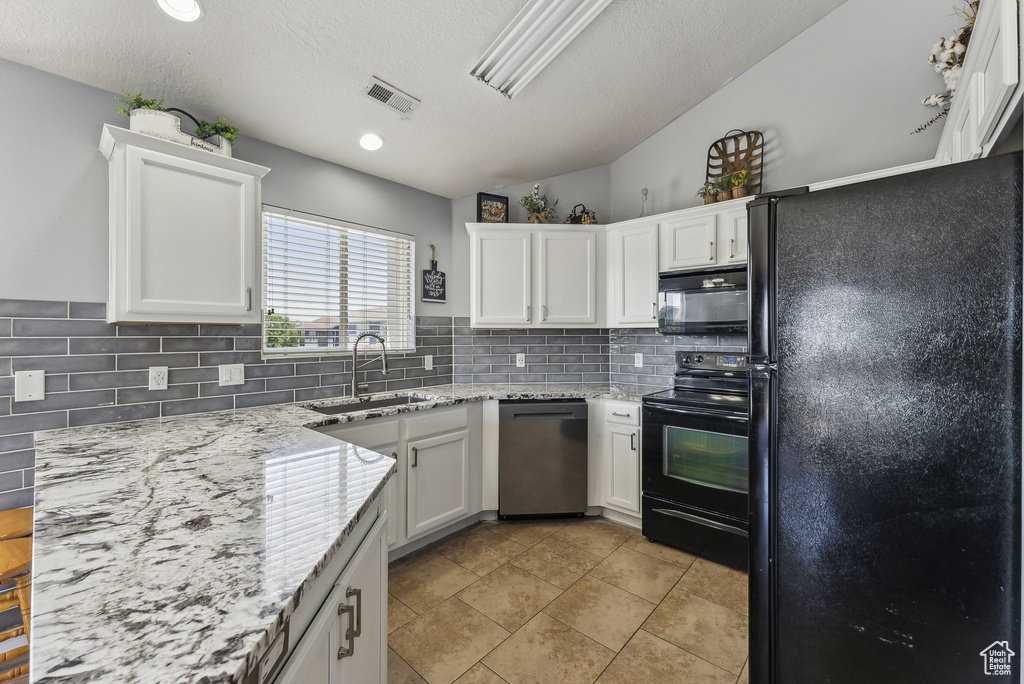 Kitchen with black appliances, a sink, decorative backsplash, white cabinetry, and a textured ceiling