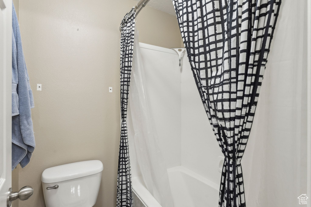 Full bathroom featuring toilet and shower / bath combination with curtain