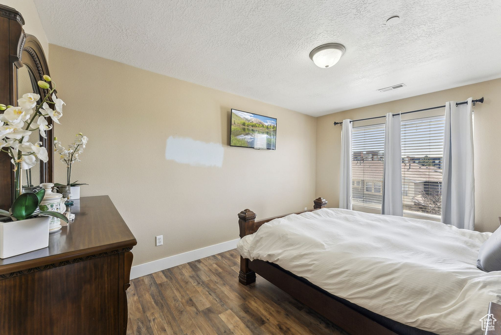 Bedroom with dark wood-style floors, baseboards, and a textured ceiling