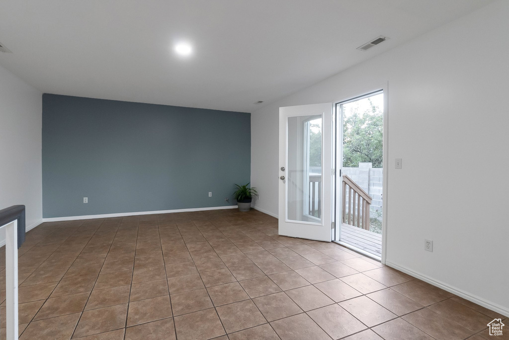 Spare room featuring tile patterned floors, vaulted ceiling, and baseboards