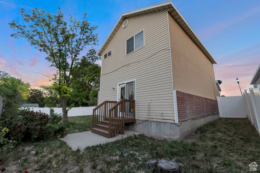 Back of property at dusk featuring brick siding and a fenced backyard