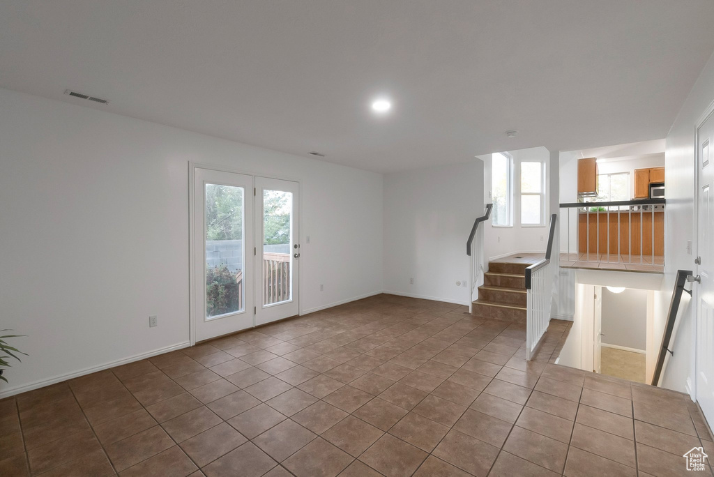Unfurnished living room with stairway, tile patterned floors, and baseboards