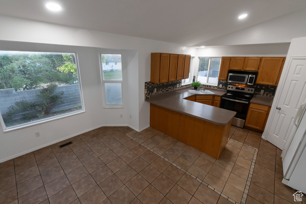 Kitchen with stainless steel appliances, decorative backsplash, a peninsula, lofted ceiling, and recessed lighting