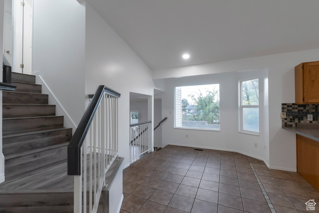 Stairway featuring tile patterned floors, baseboards, recessed lighting, and lofted ceiling