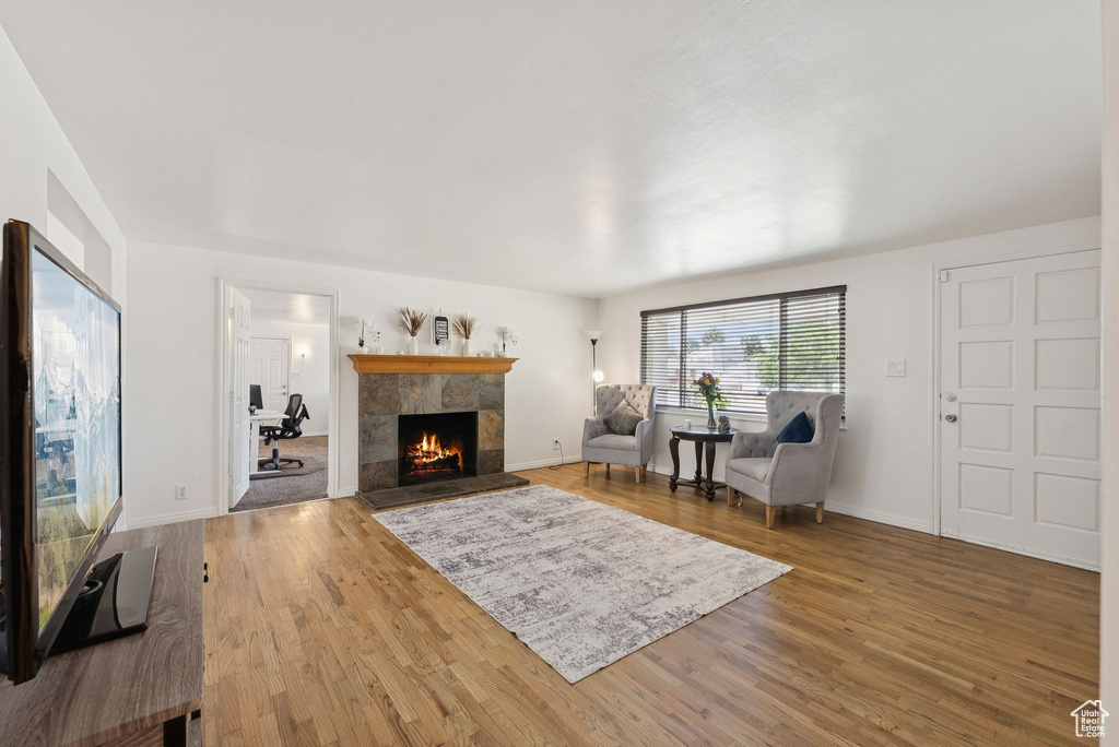 Living room featuring a tiled fireplace, wood finished floors, and baseboards