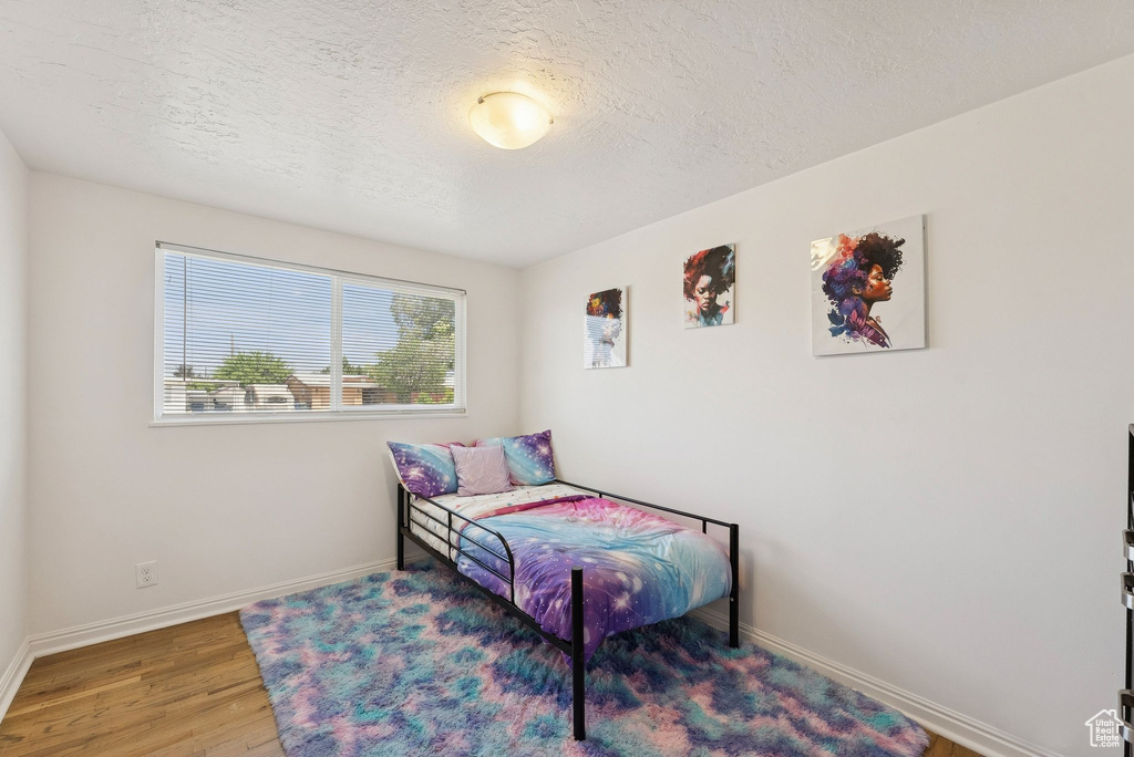 Bedroom featuring a textured ceiling, wood finished floors, and baseboards