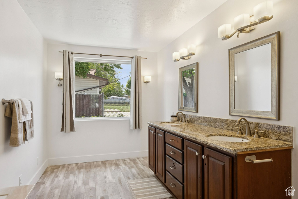 Bathroom with wood finished floors, double vanity, and baseboards