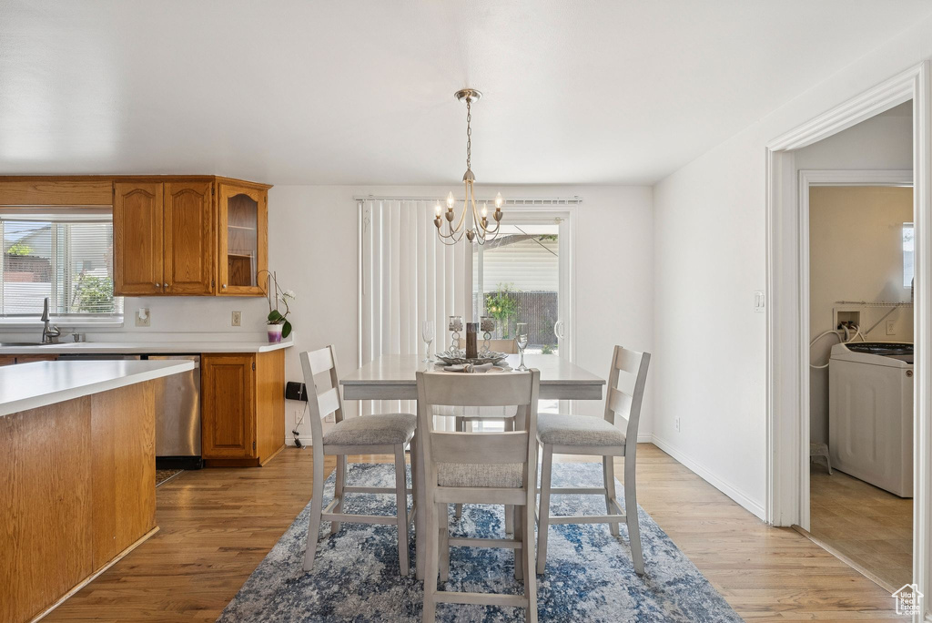 Dining room with washer / clothes dryer, a chandelier, light wood-style flooring, and baseboards